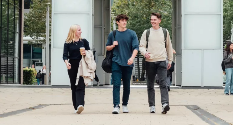 Tre unge studenter går over en plass